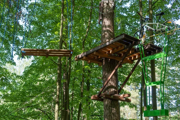 Obstacle course in the rope park at a height in the foliage of the trees. Outdoor activities. Adventure among the foliage of trees in the forest. Bike n a rope with a shifted center of gravity for balance.