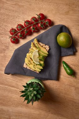 Sağlıklı vegan kahvaltısı. Koyu bir peçetenin üzerinde limonlu avokado tostu ve ahşap bir arka planda kişniş.