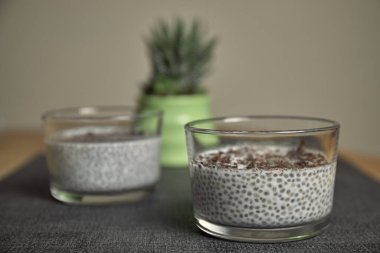 Bir bardak yulaf sütlü Chia pudingi çikolata ve mavi peçetenin üstüne çilekli talaş. sağlıklı yemek ve diyet