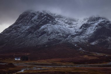 Glencoe, İskoçya 'daki alçak dağ kulübesi, Uk. Arkasında karlı dağ Stob Dearg olan tipik bir dağ binası. Büyük bir fırtınadan sonra, kışın karlı bir atmosfer