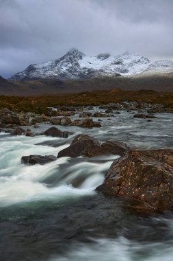İskoçya 'nın Skye Adası' ndaki Sligachan Nehri 'nde kayaların ve küçük şelalenin üzerinde uzun süre su bulunması ve kışın İskoçya' nın Skye Adası 'ndaki Cuillin dağ sırasının karla kaplı olması.