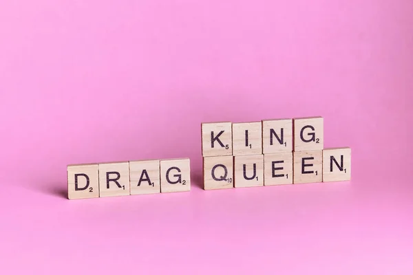 Drag Queen King Queen words represented by wooden letter tiles isolated on colour background with copy space. LGBTQ, LGBTQQIA concept.