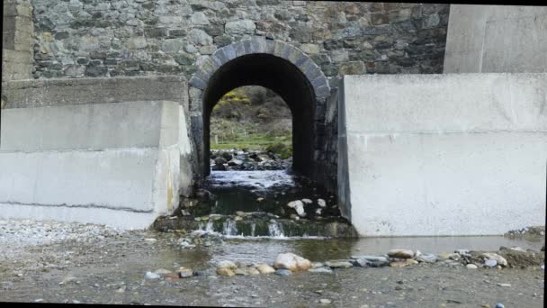 小さな小川が道路の下のトンネルを通っている。海水がビーチに流れ込み — ストック動画