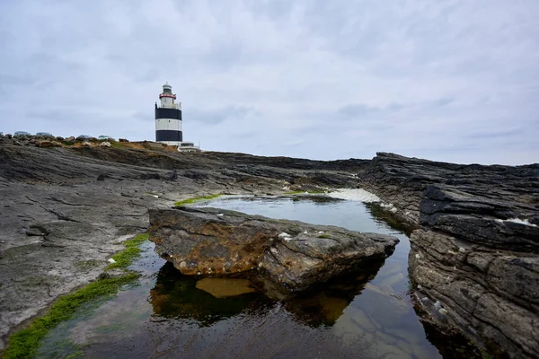 水の中に苔と反射がある岩に囲まれた古い灯台の地平線のイメージ アイルランドのウェックスフォード — ストック写真