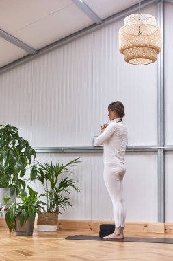 Harika bir vücudu ve güzel bir spor salonu olan bir kadın sırtüstü meditasyon yapıyor.