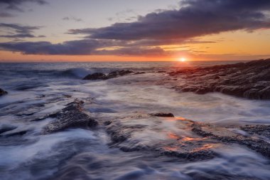 Rathmoylan Koyu, Waterford, İrlanda. Çarpıcı kayalar ve gün batımı.