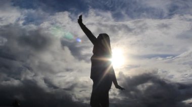 Bulutların üzerindeki kadın günbatımında geleneksel dans ederken parlıyordu.