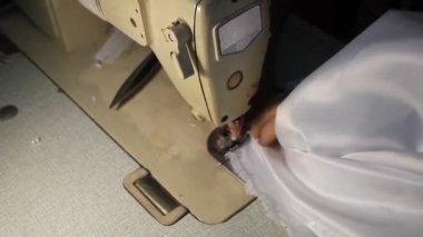 Beyaz bir elbisenin üzerinde dikiş makinesi olan el kanalizasyonu.