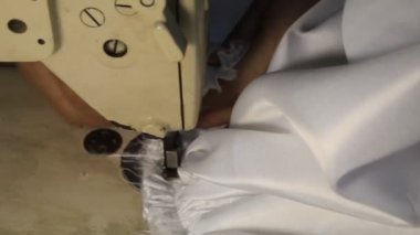 Beyaz bir elbisenin üzerinde dikiş makinesi olan el kanalizasyonu.