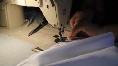 Eller dikiş makinesiyle dikiliyor Beyaz uzun bir elbisenin üzerinde