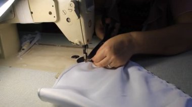 Eller dikiş makinesiyle dikiliyor Beyaz uzun bir elbisenin üzerinde