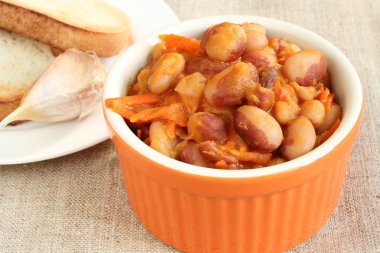 Barbunya fasulyesi yahni havuç, soğan ve portakal seramik kase keten kumaş üzerine domates sosu ile