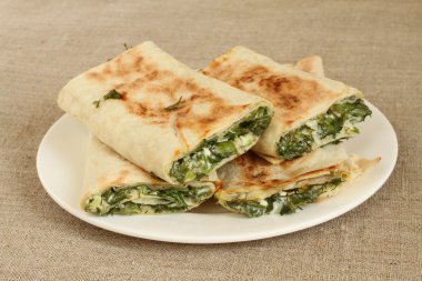 Otlar ve beyaz peynir beyaz plaka kaba keten kumaş üzerine kavrulmuş rulo ekmek silindir Mini değirmenler dolu