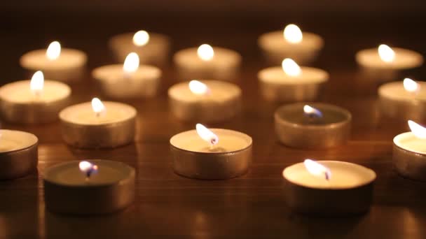 Blazing candles arranged in alignments on brown toned wooden table — Stock Video