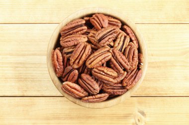 ahşap masa bambu kase içinde pekan fındık