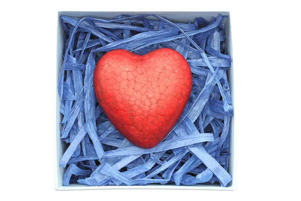 Red painted polyfoam heart enclosed with blue paper raffia strips in light blue box isolated on white background — Stock Photo, Image
