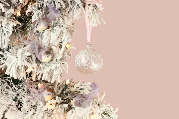 Décoration sur sapin de Noël - oiseaux violets clairs et boule vitreuse sur épinette neigeuse sur fond rose — Photo