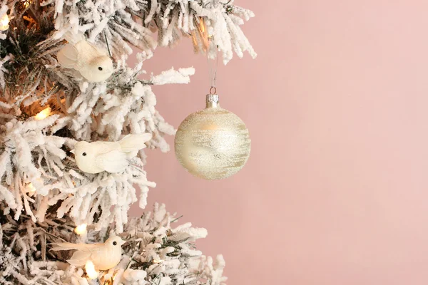 Décoration sur sapin de Noël - oiseaux blancs et boule d'argent sur épinette neigeuse sur fond rose — Photo