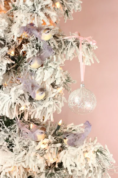 Decoration on Christmas tree - light violet birds and glassy ball on snowy spruce on pink background — Stock Photo, Image