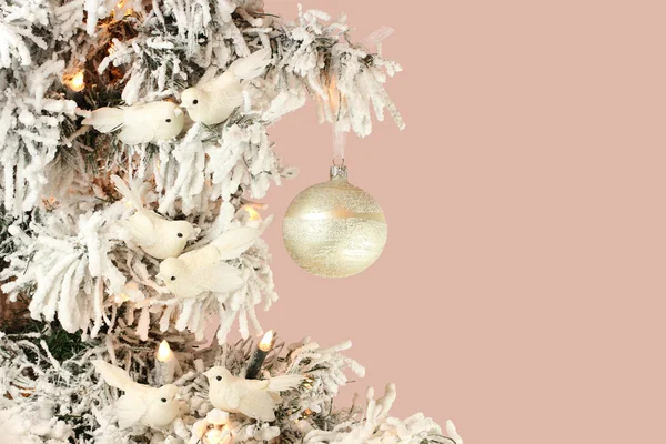 Decoration on Christmas tree - white birds and silver ball on snowy spruce on pink background — Stock Photo, Image