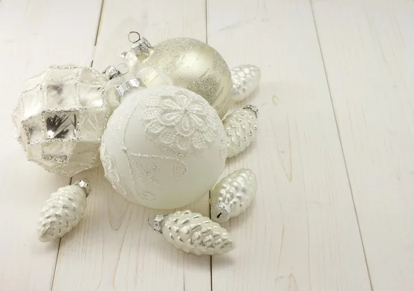 Toys for Christmas decoration - white and silver balls and silver cones on white wooden background
