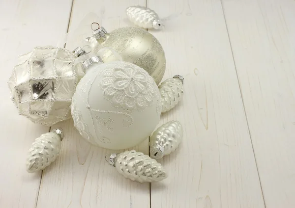 Toys for Christmas decoration - white and silver balls and silver cones on white wooden background — Stock Photo, Image