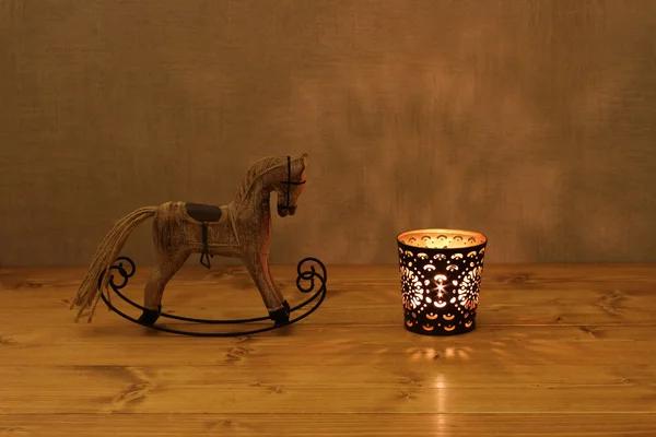 Boże Narodzenie dekoracje - drewniane zabawki na biegunach koń i świeca w Świecznik na drewnianym stole z betonową ścianą — Zdjęcie stockowe