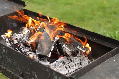 Köz mangal yeşil çim arka plan karşı yanan