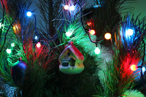 Ghirlanda illuminata di anno nuovo e casa su pino-albero. Primo piano — Foto Stock