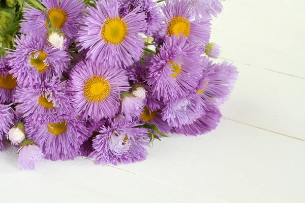 Bouquet of light purple flowers on white painted wooden table. Closeup