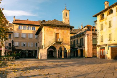 Historic Main Square of Orta San Giulio at Sunset. A view of the main square of Orta San Giulio with its iconic church and historic buildings illuminated by soft sunset light. A strong editorial and travel-oriented image.