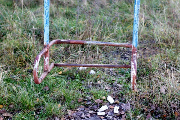 Velho balanço quebrado abandonado enferrujado, grama seca outono, tinta verde e vermelho gasto — Fotografia de Stock