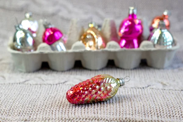 Alte sowjetische Dekoration am Weihnachtsbaum, Glasspielzeug-Tannenzapfen in Großaufnahme auf gestricktem verschwommenem Hintergrund — Stockfoto