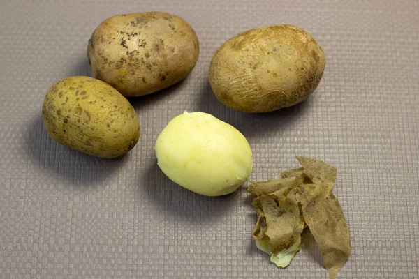 Boiled yellow potatoes in jackets on a light texture background, close-up