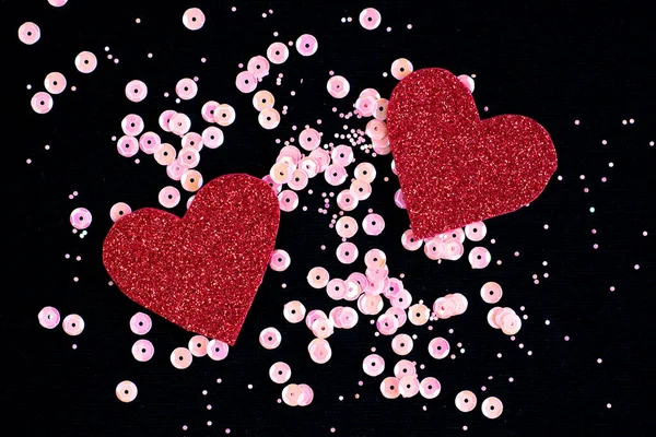 Dwa błyszczące serca wycięte z papieru na czarnym tle z różowymi iskrami — Zdjęcie stockowe