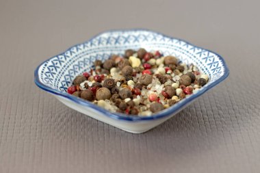 Açık gri keten arka planda deniz tuzu ve baharatlar küçük mavi tabakta, kırmızı biber, defne yaprağı, yakın plan,