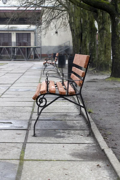 Gyönyörű kovácsolt barna park pad a háttérben egy régi épület — Stock Fotó