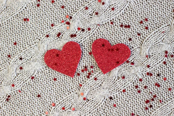 Two shiny hearts cut out of red paper on a cozy knitted background with red sparkles — Stock Photo, Image