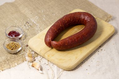 Ahşap kesme tahtasındaki iştah açıcı sosis sert keten arka planda acı biber ve baharatla, kapat.