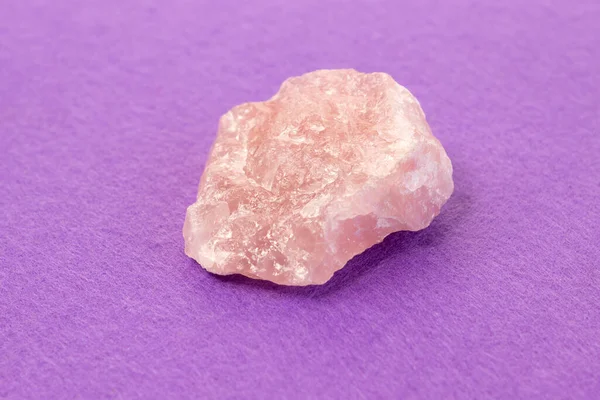 Pezzo di quarzo rosa lucido su sfondo viola. Natura morta di colore minimo Linea di messa a fuoco stretta, profondità di campo poco profonda — Foto Stock