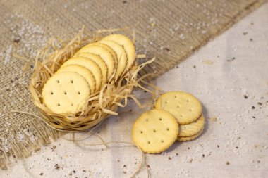 Kaba keten kumaş üzerinde tuzlu bisküvi krakeri saman sepetinde dar odak çizgisini kapat, sığ alan derinliği