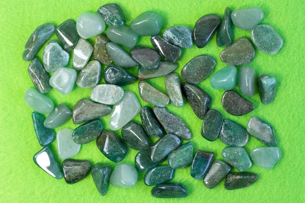 Macrofoto del espécimen de roca mineral: gemas de aventurina verde tumbadas sobre fondo verde parcialmente enfocadas — Foto de Stock