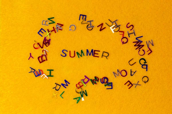 Pequeñas letras multicolores brillantes esparcidas verano sobre un fondo amarillo —  Fotos de Stock