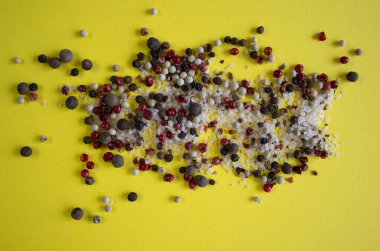 Baharatlar, beyaz, siyah ve kırmızı biberler, cam tabakta deniz tuzu, sarı arka plan, yakın çekim üst görüş
