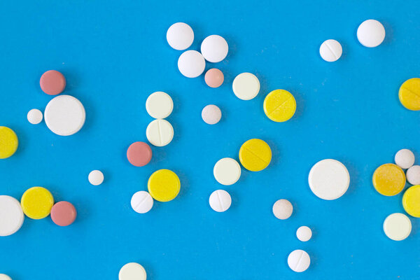 Group of colorful pills as nice light blue textured background Narrow focus line, shallow depth of field