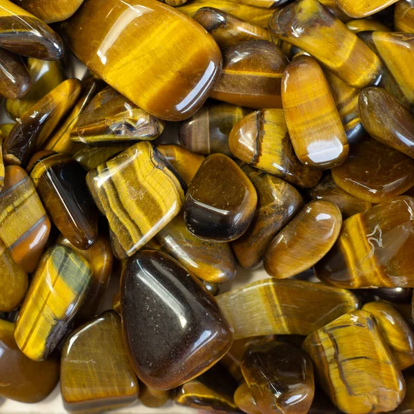 Doğal mineral taşı, kaplan gözü, kaplan gözü, açık bej arka planda kaplan gözü taşı.