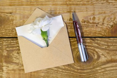 Ahşap arka planda beyaz çiçekli basit küçük bir zarf. Dar bir kalem odaklı çizgi, sığ alan derinliği yüksek açı görüşü.