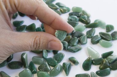 Doğal mineral kaya numunesinin makroshoplaması - beyaz bulanık arka planda el ile yuvarlanan yeşil bulvar taşı