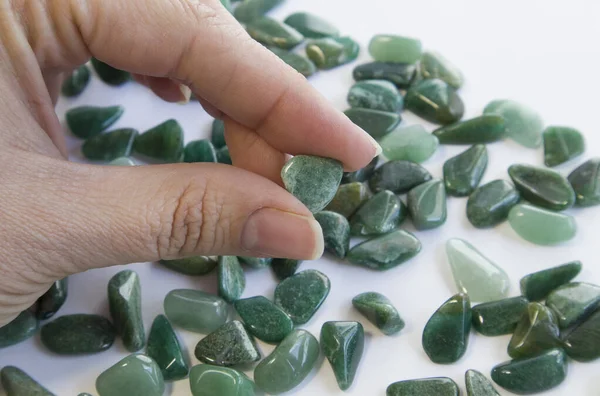 Doğal mineral kaya numunesinin makroshoplaması - beyaz bulanık arka planda el ile yuvarlanan yeşil bulvar taşı