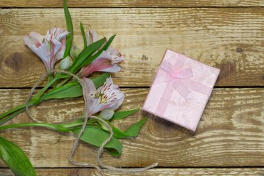 Parlak beyaz ve pembe çiçekler Alstroemeria ve ahşap desenli arka plan yakın plan üzerine paketlenmiş pembe kağıt hediye paketi